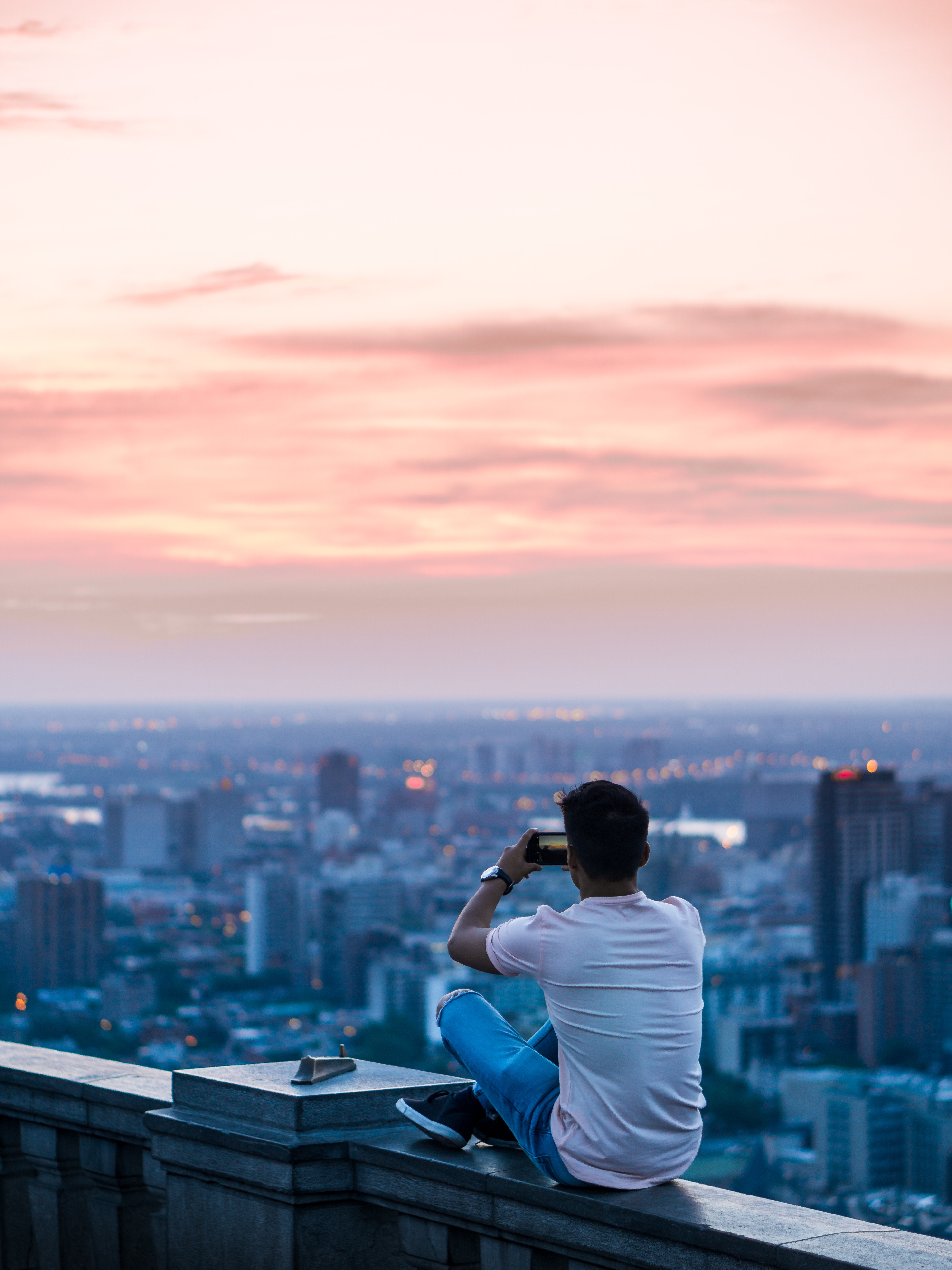 A male photographer taking a picture of the city skyline.